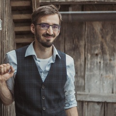 Portrait photograph of Dr Philipp Preinstorfer, a man with brown hair, a beard and glasses leaning against a timber building.  